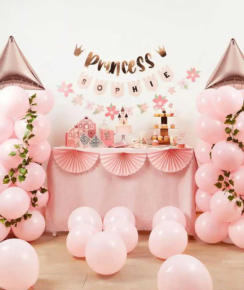 Princess-themed party display with pink balloons, a dessert table, castle decorations, cupcakes, and a personalised princess birthday banner.